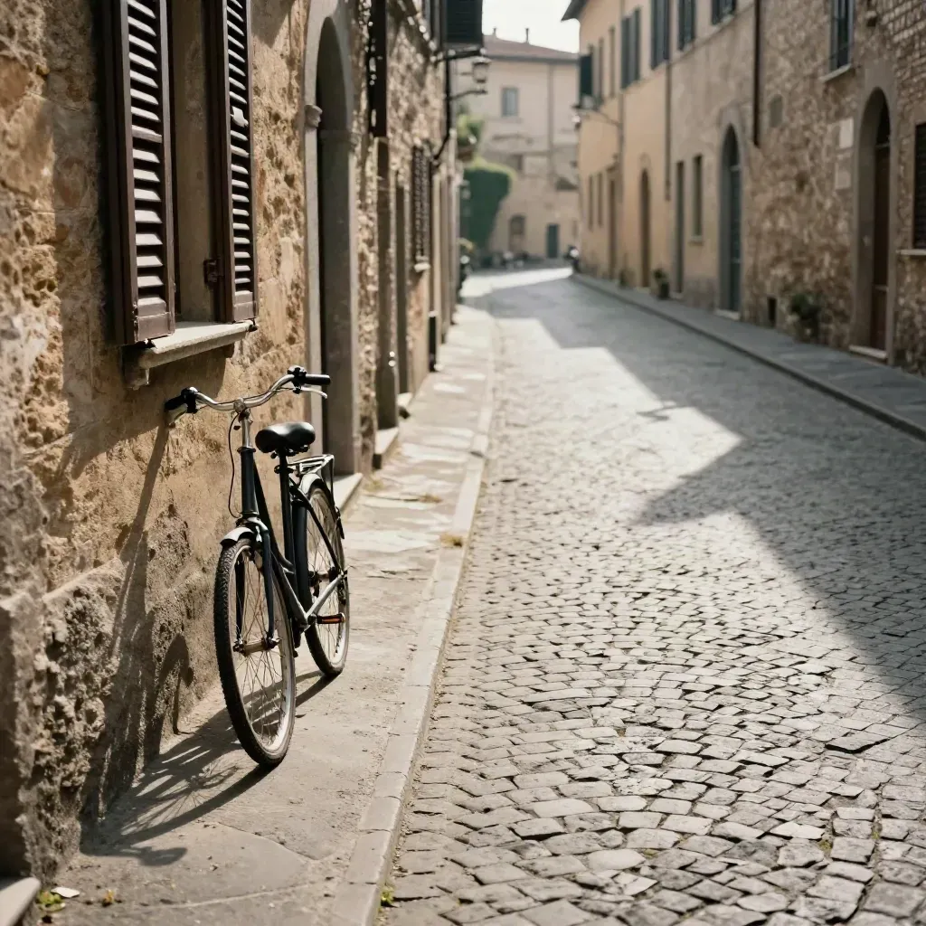 Vicolo senese vuoto con bici al muro, ombre lunghe e luce calda del tardo pomeriggio.